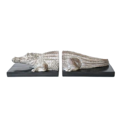 SILVER CROCODILE BOOKENDS PAIR 10X42X12CM Expertly crafted with precision, this pair of Silver Crocodile Bookends adds a touch of elegance to any bookshelf or desk. Made of high-quality materials, these bookends are both stylish and functional, helping to keep your books organized and in place. A must-have for any avid reader or lover of luxury decor.  Delivery 5 to 7 working days