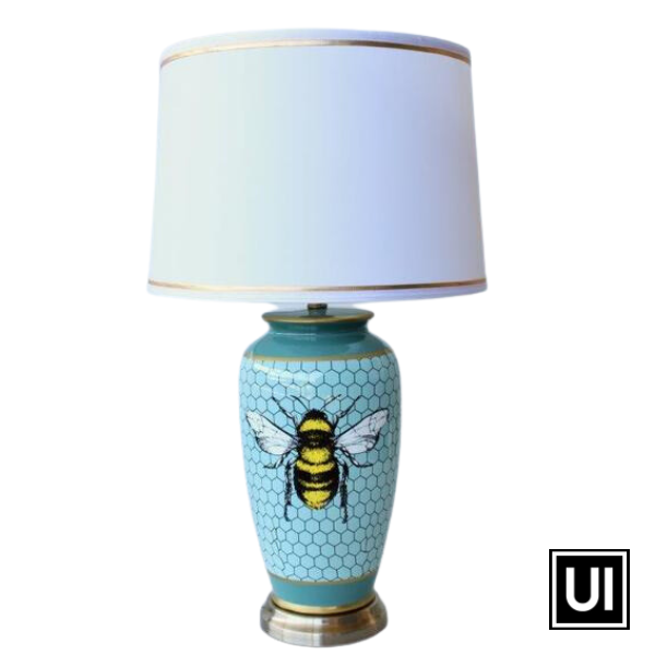 Introducing our blue honeycomb bee lamp base with a white shade and gold trim from Unique Interiors. Standing at an impressive 68cm tall and 40cm in diameter, this lamp base is made with the highest quality ceramic and hand-crafted to perfection.  The blue honeycomb bee design creates a unique and eye-catching look that is perfect for adding a touch of whimsy to any room in your home. The white shade with gold trim complements the base beautifully, providing a warm and inviting glow.